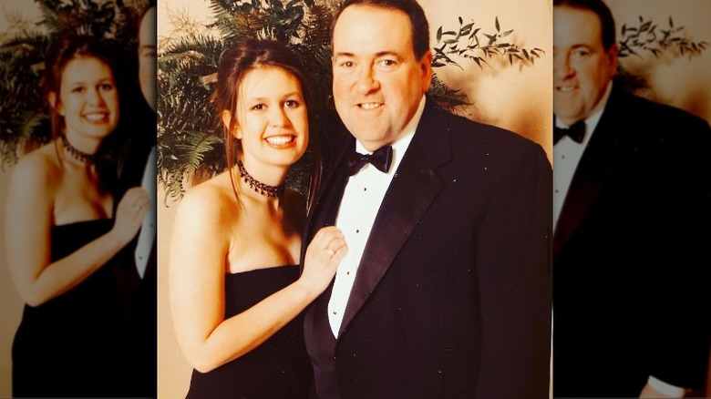 A young Sarah Huckabee Sanders posing with Mike Huckabee at a black tie event