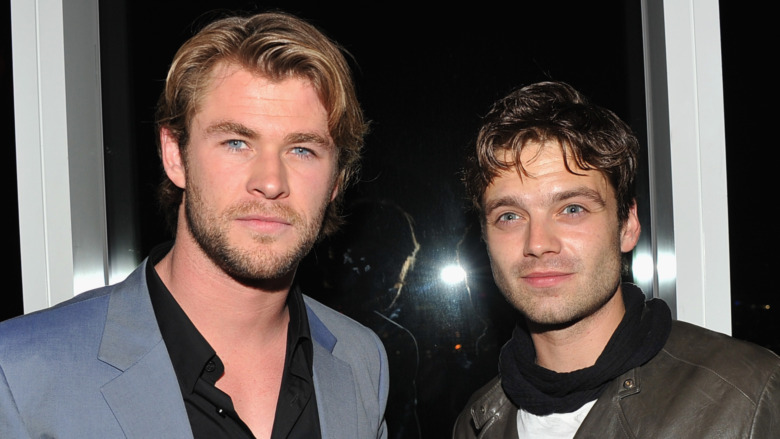 Chris Hemsworth and Sebastian Stan posing for cameras, with Stan looking up and to his right