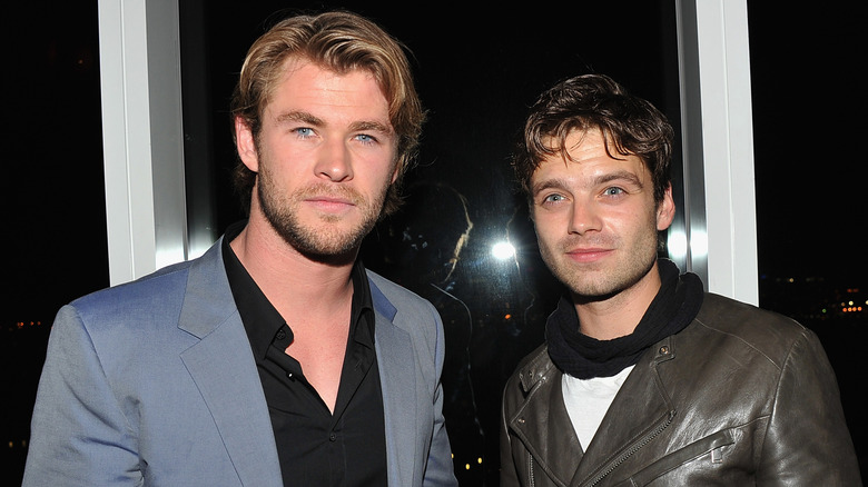 Chris Hemsworth and Sebastian Stan posing for cameras, with Stan looking up and to his right