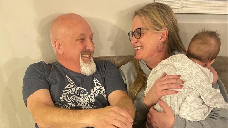 Christine Brown and David Woolley smile at each other as Christine holds one of their grandkids