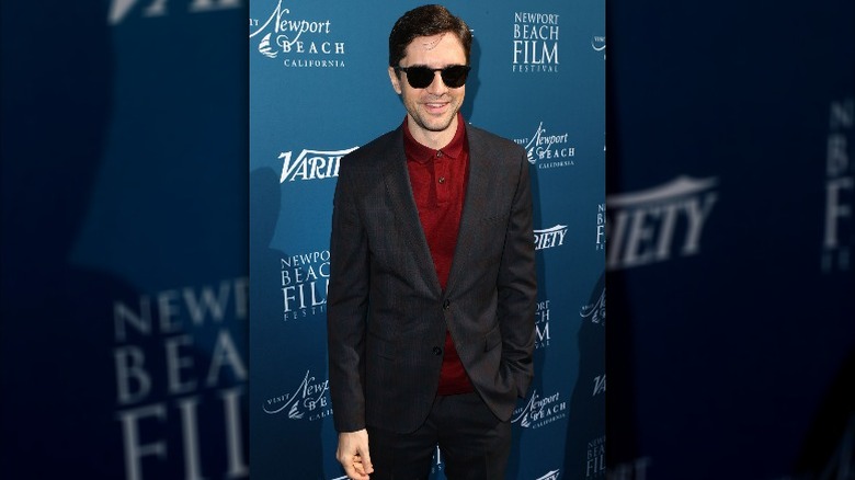 Topher Grace wearing suit and shades