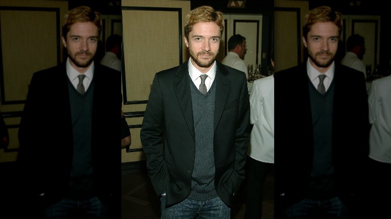 Topher Grace wearing tie, sweater