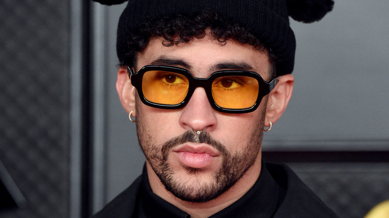 Bad Bunny, wearing yellow sunglasses, not smiling, wearing a hat, 2021 red carpet award show