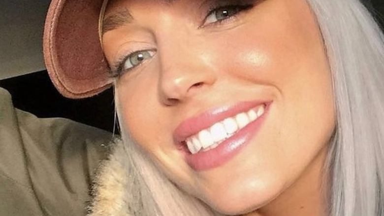 Alex Cooper smiling and wearing baseball cap