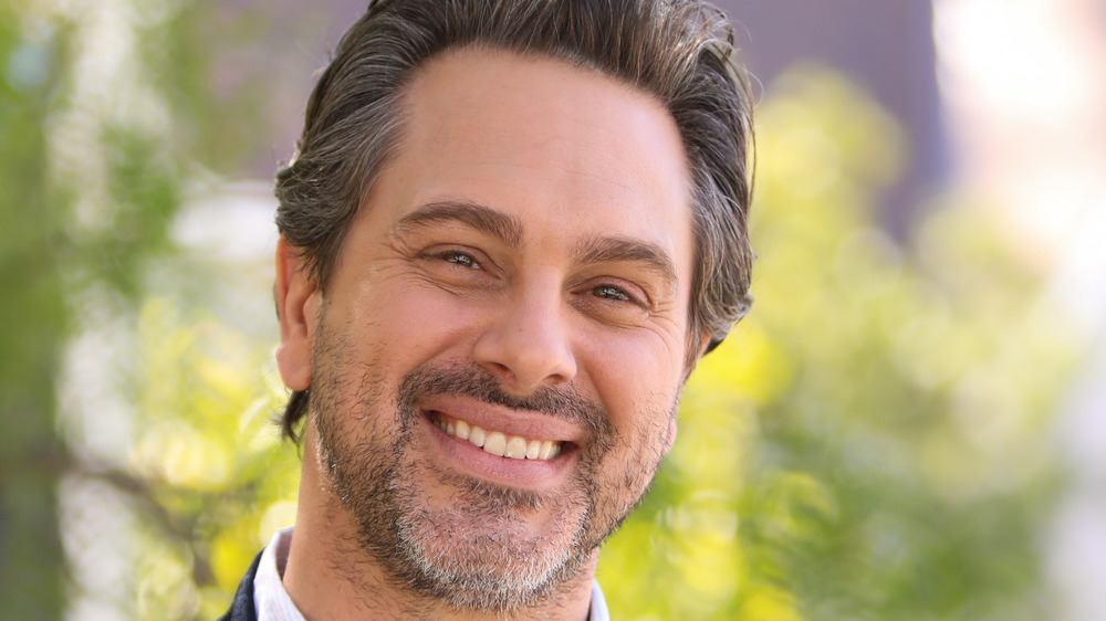 Thomas Sadoski, smiling, outside, in a collared shirt, facial hair