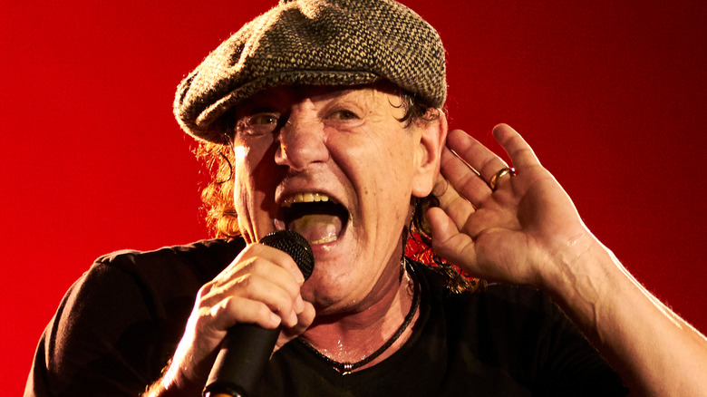 Angus Young shouts into a microphone on stage