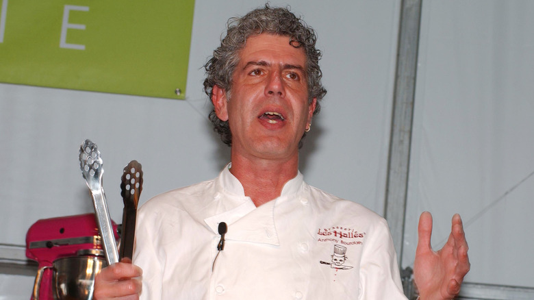 Anthony Bourdain holding tongs