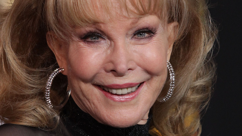 Barbara Eden smiles while wearing hoop earrings