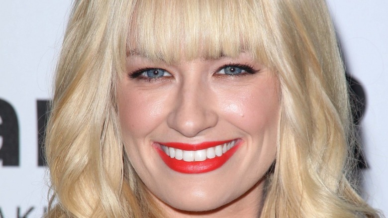 Beth Behrs with wide smile and red lipstick