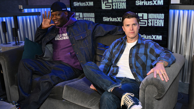 Colin Jost And Michael Che sitting on a couch on "The Howard Stern Show" set