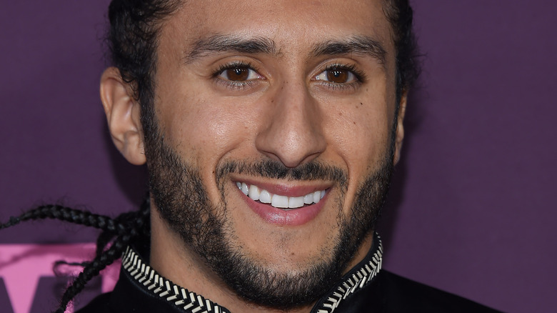 Colin Kaepernick smiles in a dark outfit