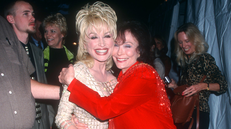 Loretta Lynn and Dolly Parton smiling and hugging