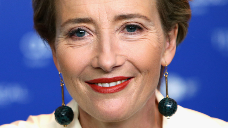 Emma Thompson poses in red lipstick and drop earrings.