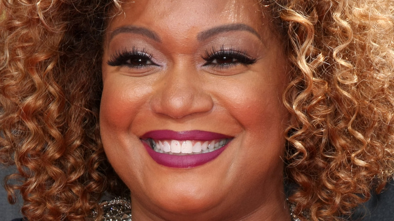 Sunny Anderson smiles in plum-colored lipstick.