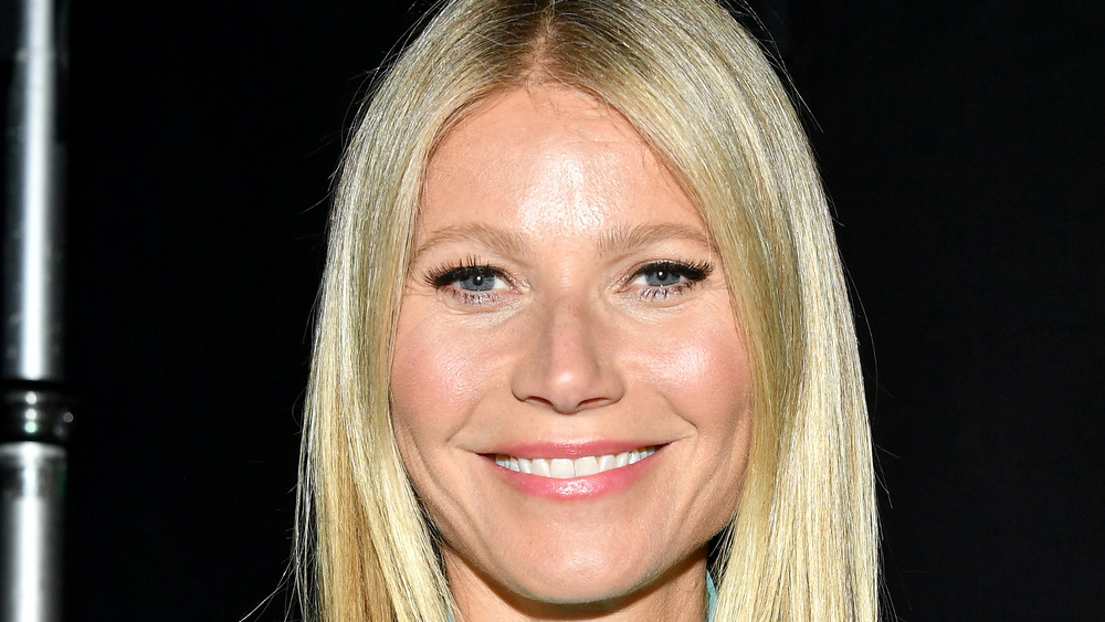 Gwyneth Paltrow smiling wide with her hair parted down the middle