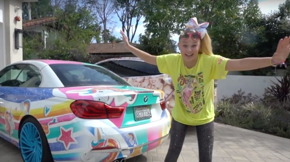 JoJo Siwa standing beside her colorful car