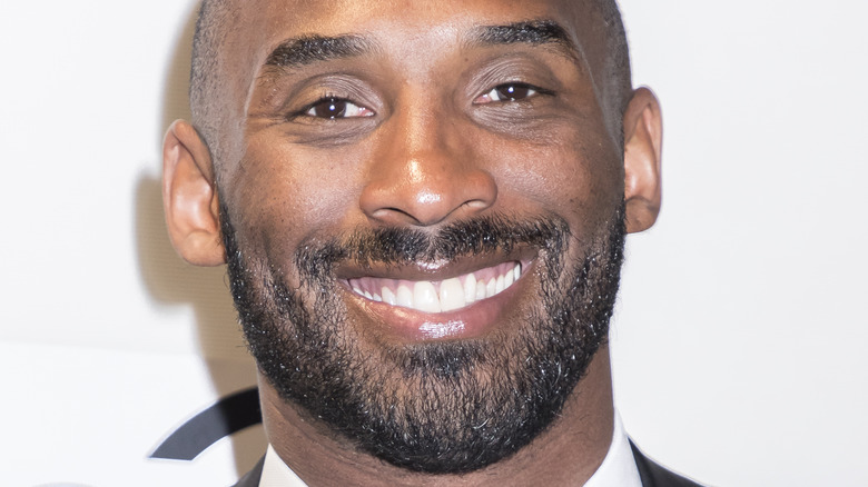 Kobe Bryant in a shirt and tie smiling 