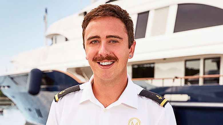 Lloyd Spencer in crew uniform in front of ship