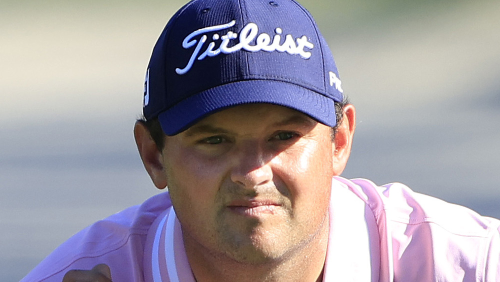 Patrick Reed squatting on the golf course