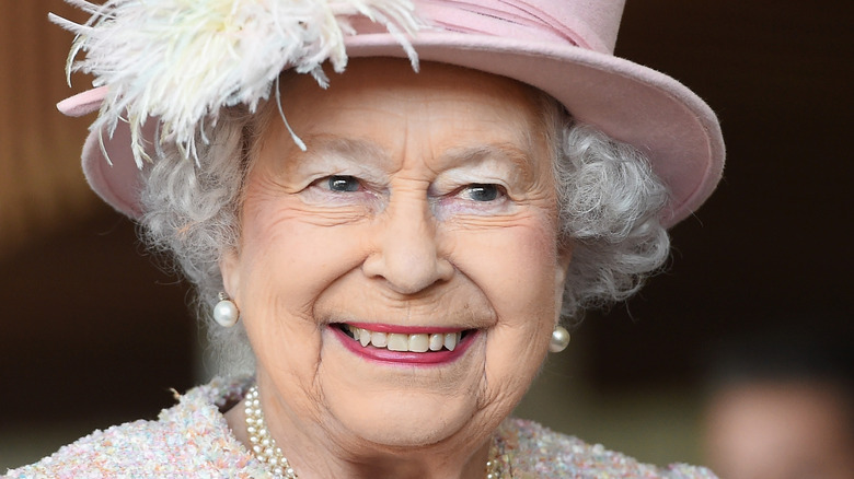 Queen Elizabeth II smiling in pink hat