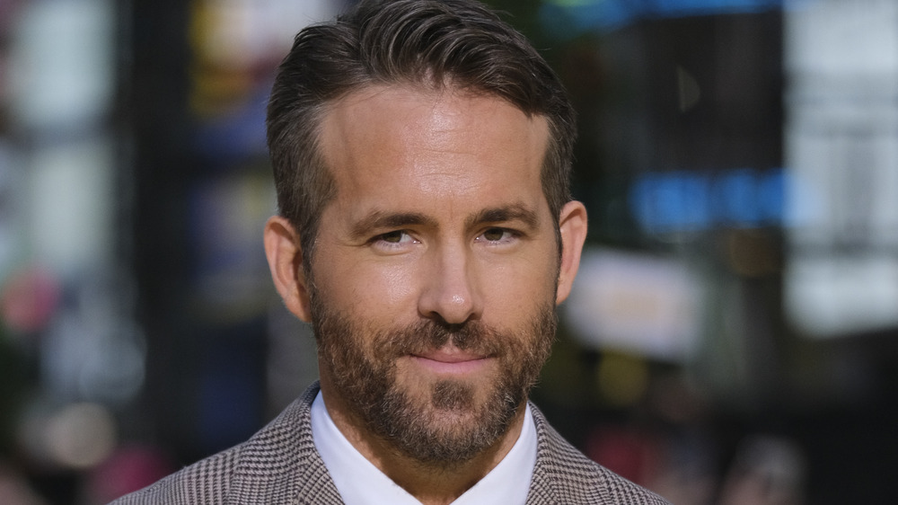 Ryan Reynolds smiles for a photo on the red carpet with his black hair swept up