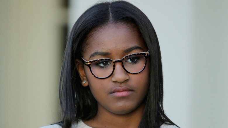 Sporting parted hair and a set of animal print glasses, Sasha Obama looks away from the camera.