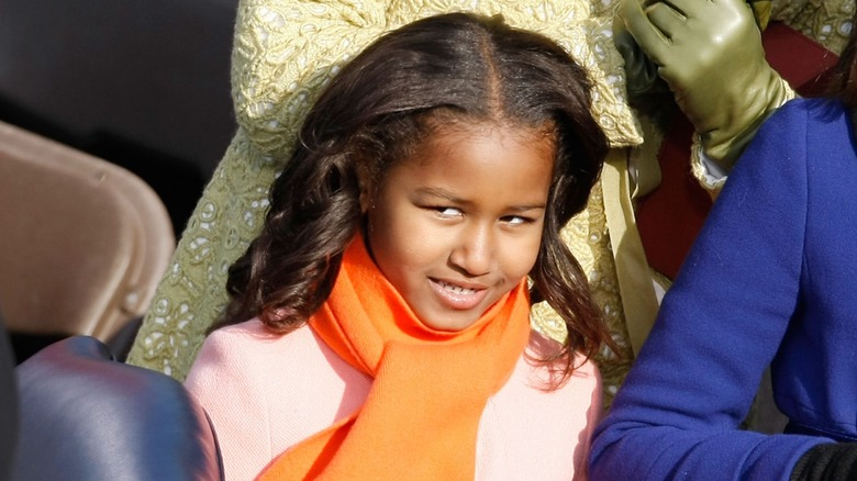 Dressed in a pink coat and an orange scarf, young Sasha Obama gives a side eye while all smiles.