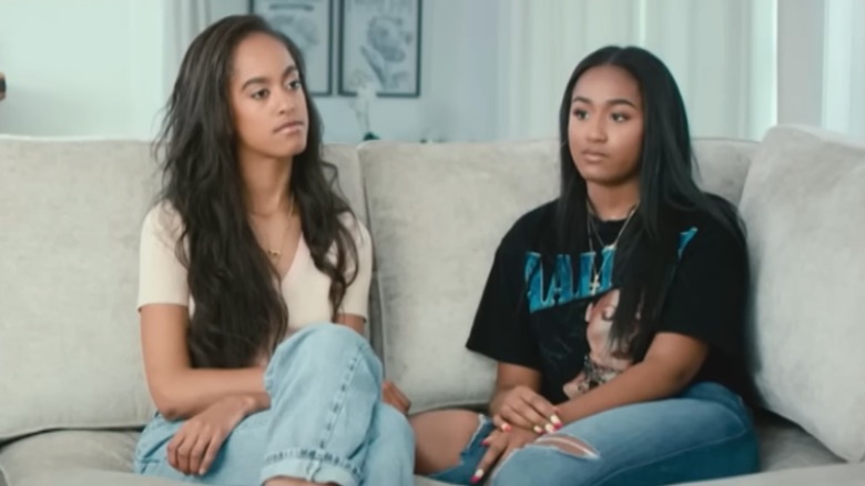 Sasha Obama speaks while seated on a couch besides her sister, Malia Obama.