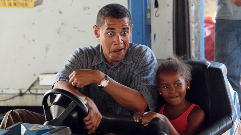 Young Sasha Obama and her father, Barack Obama make faces while Barack is behind the wheel of a ride.