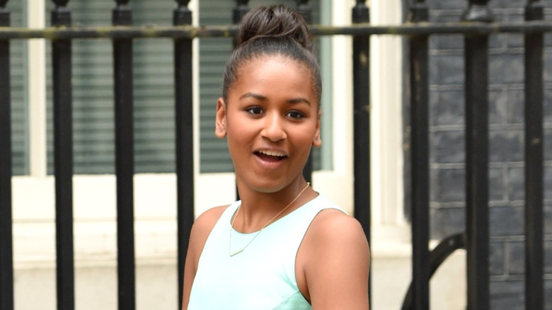 Wearing a sleeveless blue dress and a cute bun, Sasha Obama makes a face.