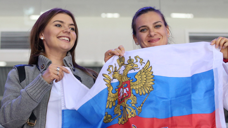 Alina Kabaeva (left) holding flag at the Olympics