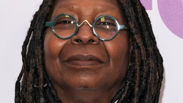 Whoopi Goldberg poses in green, round frame glasses.