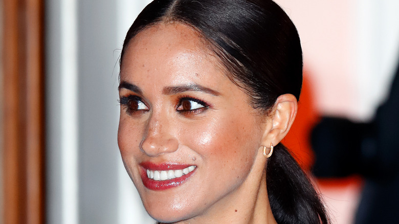 Meghan Markle, the Duchess of Sussex, smiling and looking to the side