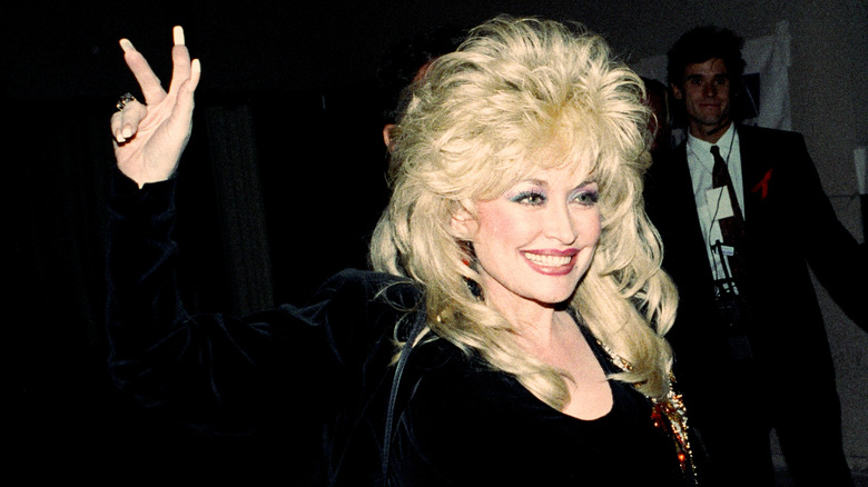 Dolly Parton holding hand up