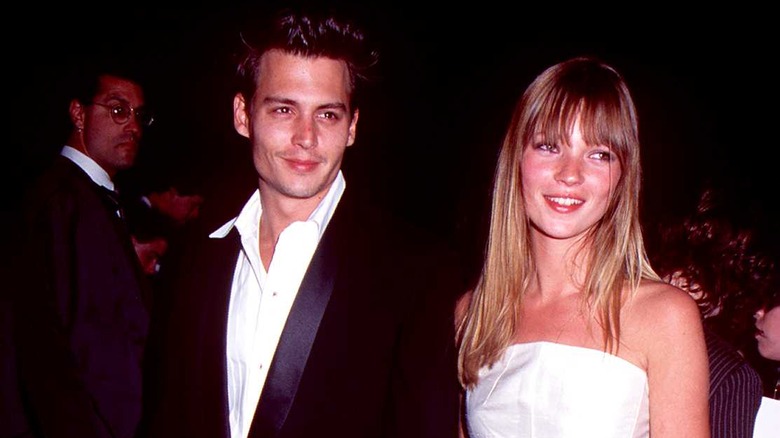 Johnny Depp and Kate Moss smiling while holding hands
