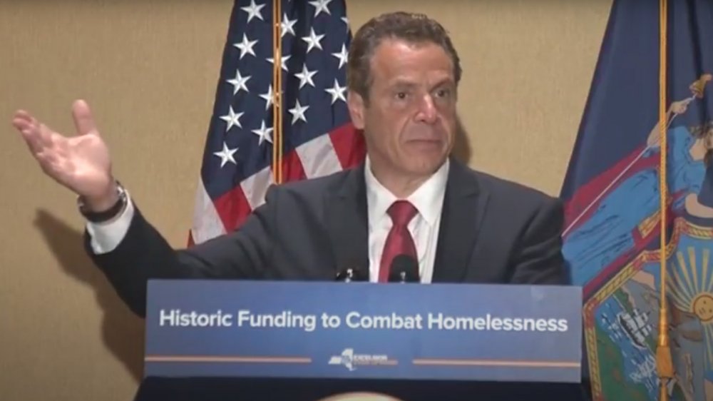 Andrew Cuomo speaking at a podium and gesturing with his hands