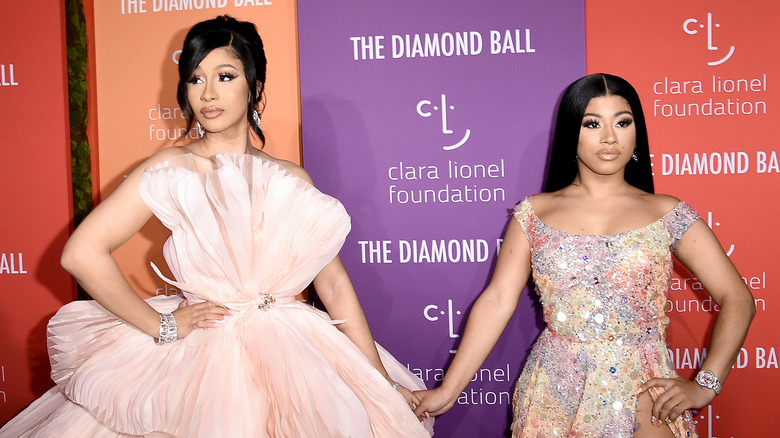 Cardi B and Hennessy Carolina with arms on hips and holding hands