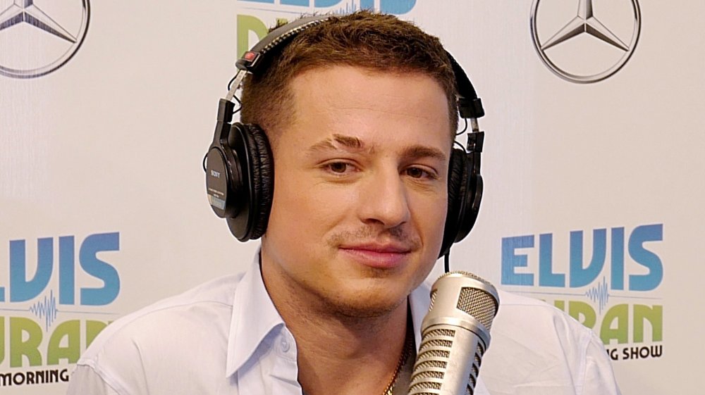 Charlie Puth wearing headphones and a white button-down shirt during an Elvis Duran interview
