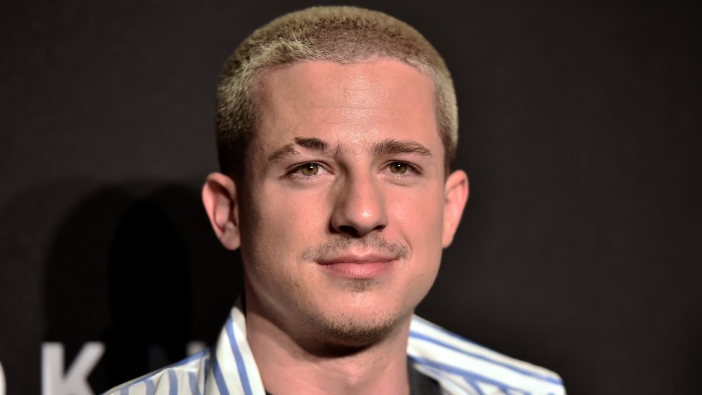 Charlie Puth in a blue-and-white striped button down, with a small smile at an event