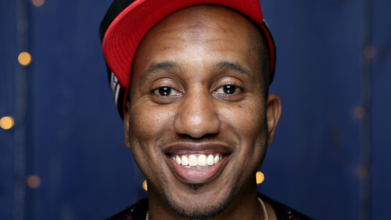 Chris Redd smiling and wearing red hat