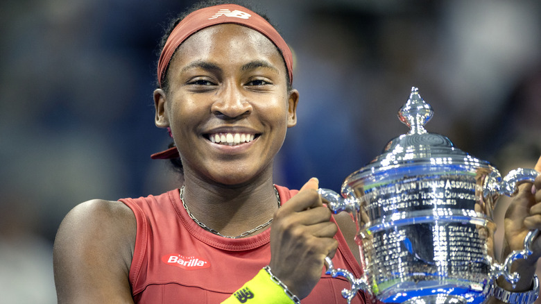 Coco Gauff smiling and holding her U.S. Open trophy