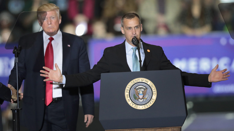 Corey Lewandowski speaks at a rally while Trump stands behind him