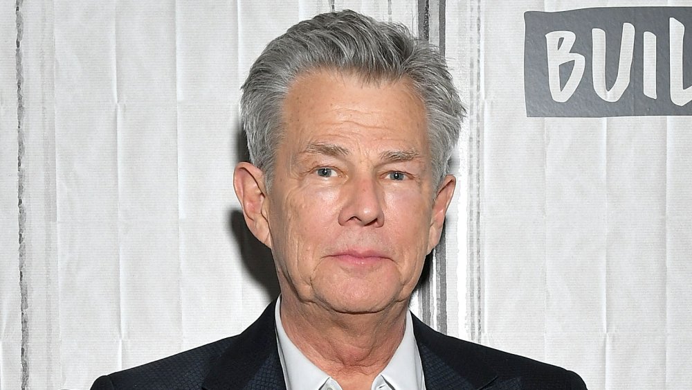 David Foster a black blazer, white shirt combo, with a neutral expression at an event