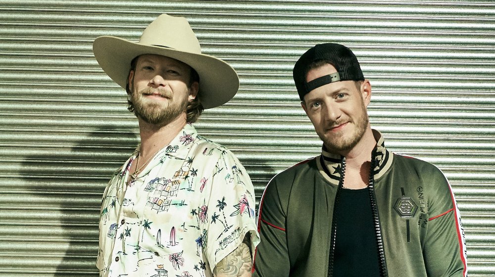 Brian Kelley smling with cowboy hat on next to Tyler Hubbard 