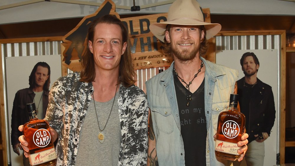 Brian Kelley and Tyler Hubbard both holding Old Camp whiskey bottles