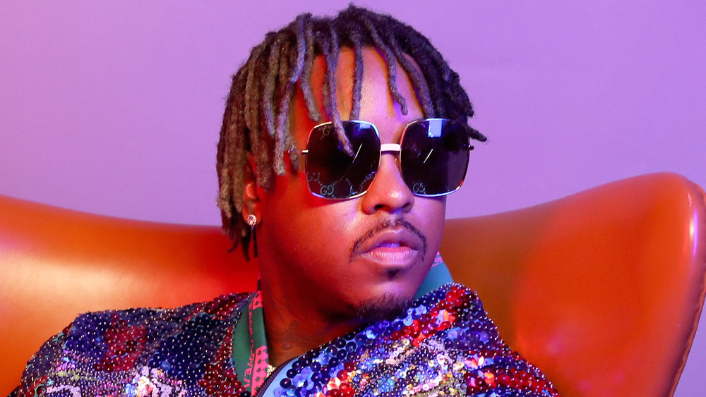 Jeremih in sunglasses and a bejeweled outfit, sitting in a chair