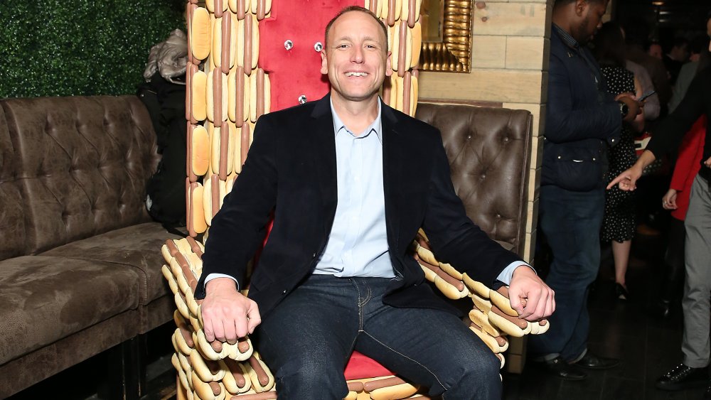 Joey Chestnut smiling and sitting on a hot dog throne