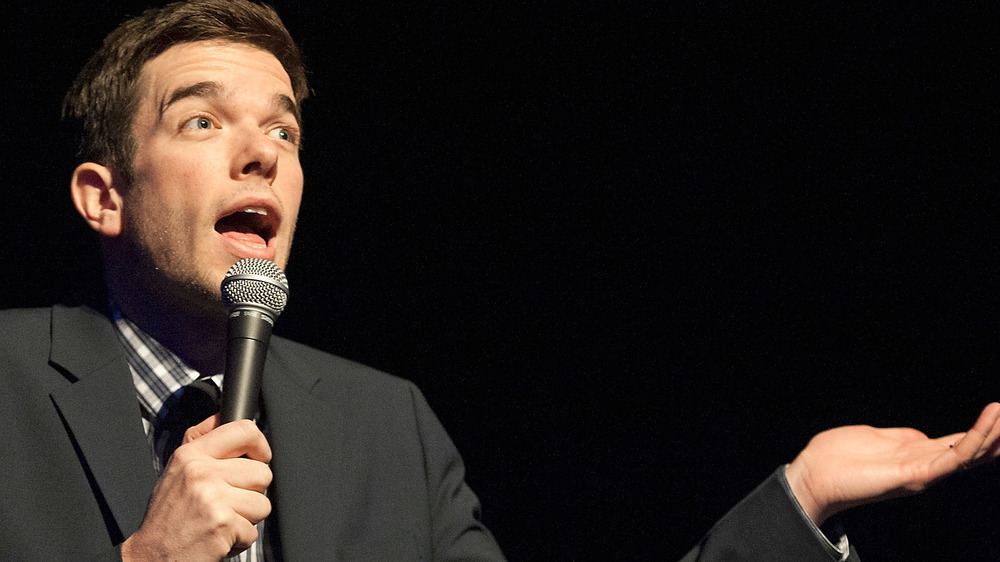 John Mulaney on stage with microphone, speaking