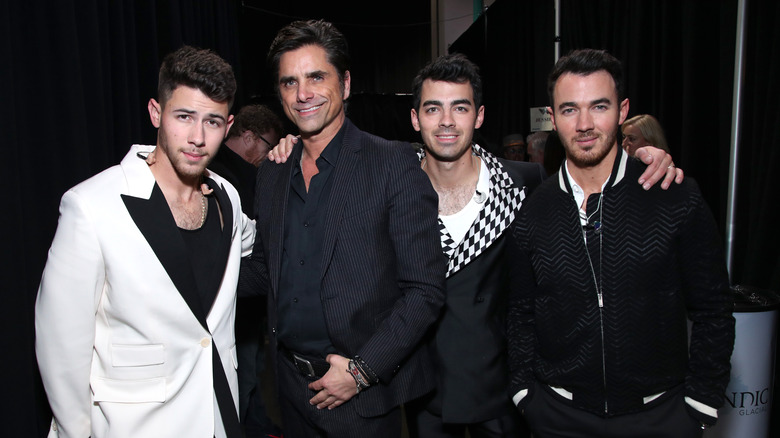 John Stamos with the Jonas Brothers, smiling