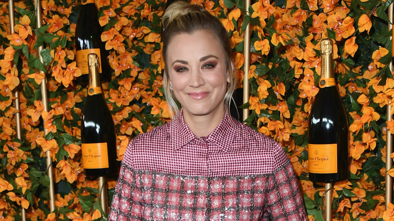 Kaley Cuoco in front of wall of flowers